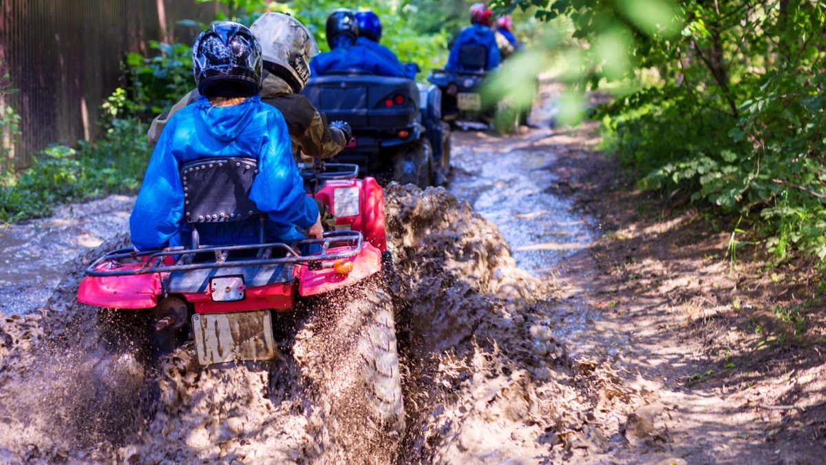 Quad riders following one another along a dusty track between trees near Pattaya
