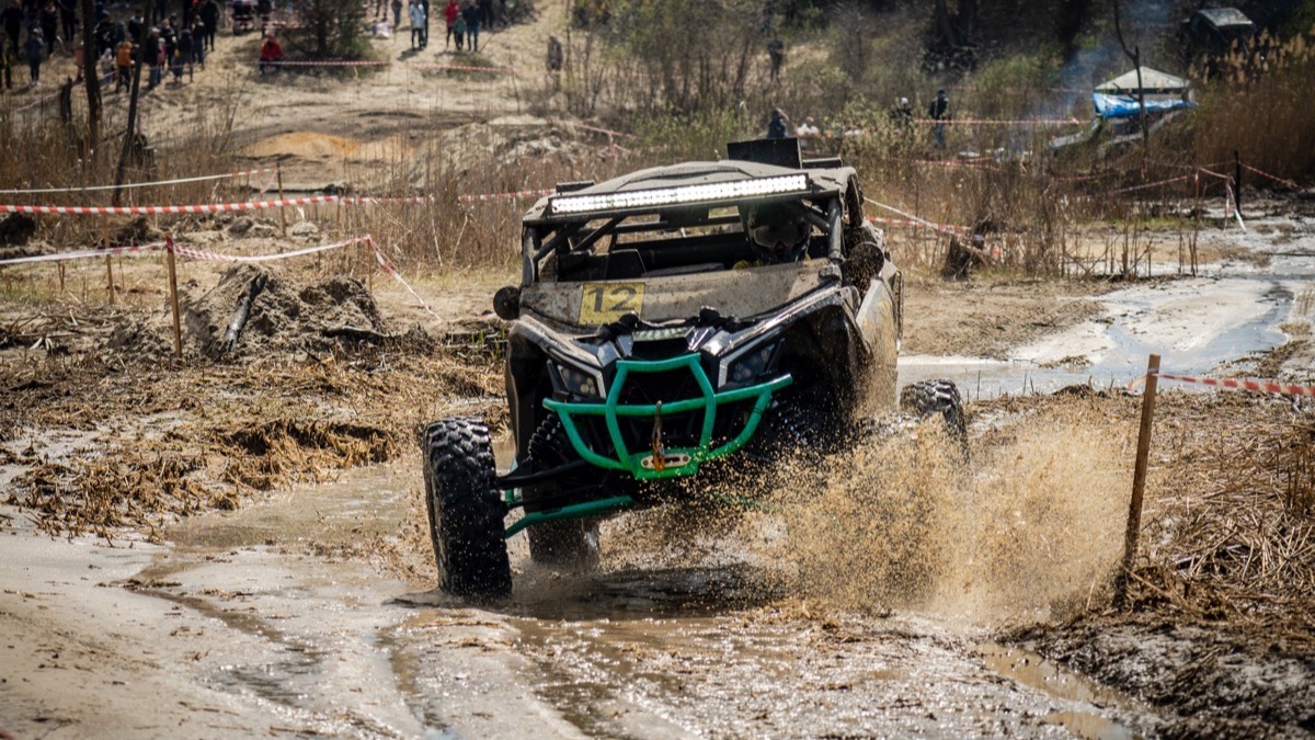 Quad bike crossing a stretch of muddy brown water on a jungle trail during the Pattaya rainy season