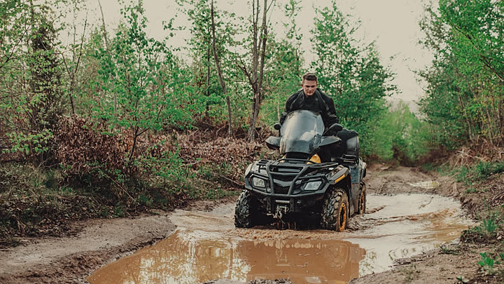 Rider in helmet and goggles on a quad bike on a muddy track