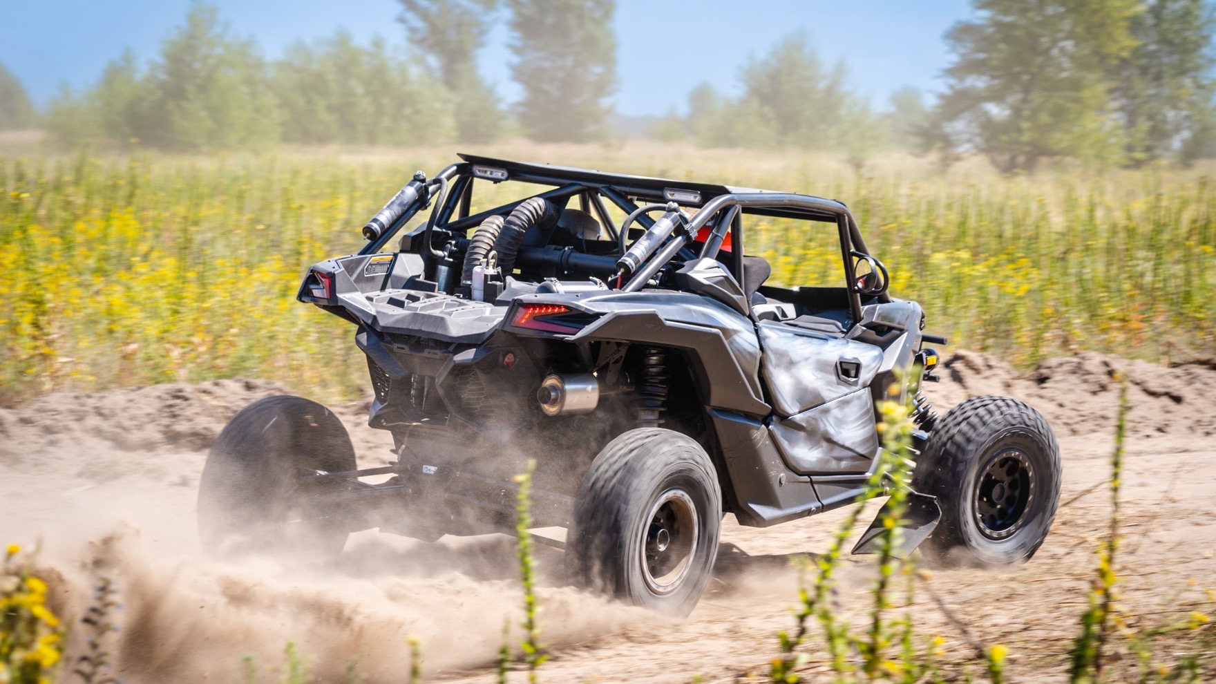 Four-seater off-road buggy with a full roll cage kicking up dust on a rough dirt track through the jungle near Pattaya
