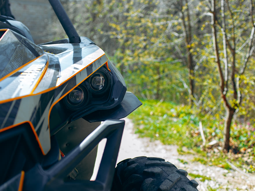 Close-up of an off-road buggy's front end with roll cage and knobbly tyres on a forest track